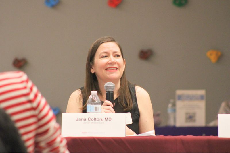 A speaker holding a microphone and smiling while answering questions at the 2025 Street Psychiatry Conference.